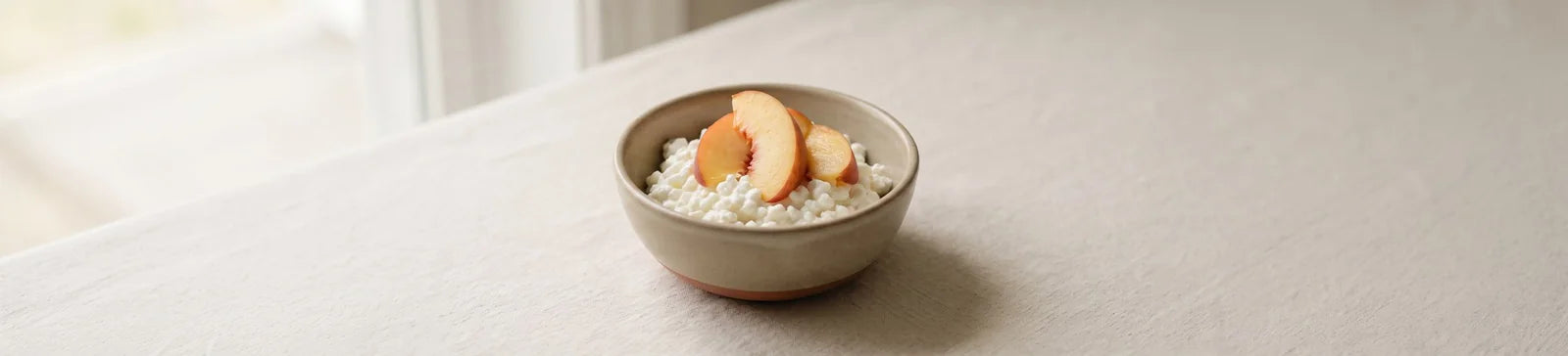 A bowl of cottage cheese topped with fresh peach slices