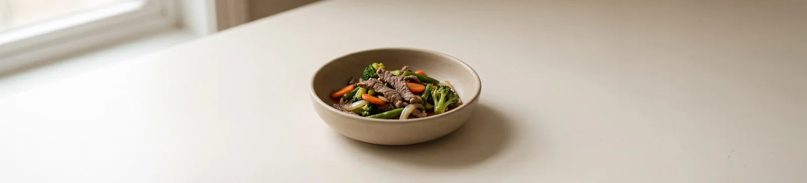 A bowl of beef stir-fry with broccoli, carrot and red pepper