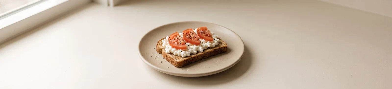A slice of whole-wheat toast spread with cottage cheese and topped with tomato slices