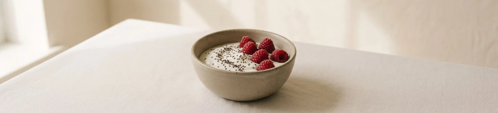 A bowl of plain Greek yogurt topped with chia seeds and raspberries