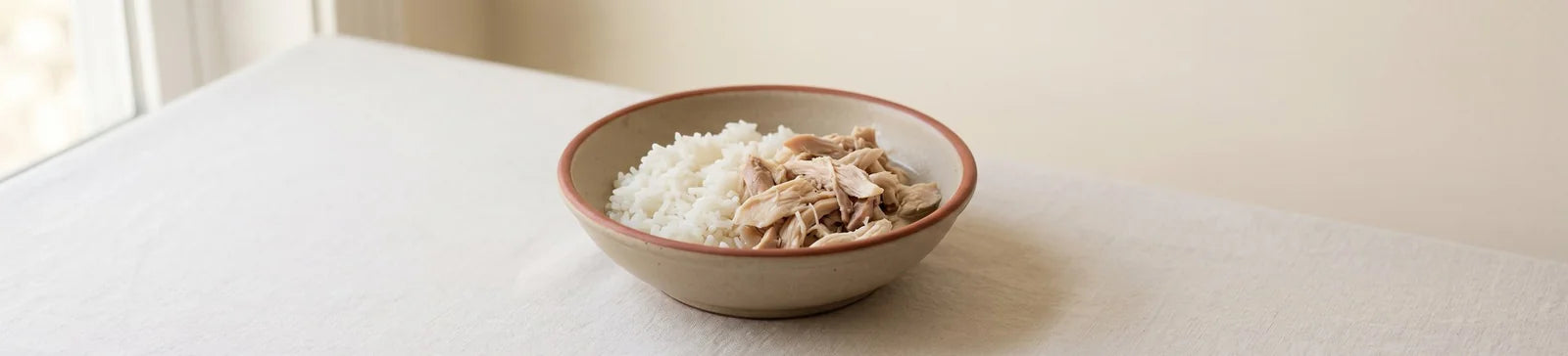 A bowl of white rice topped with shredded rotisserie chicken